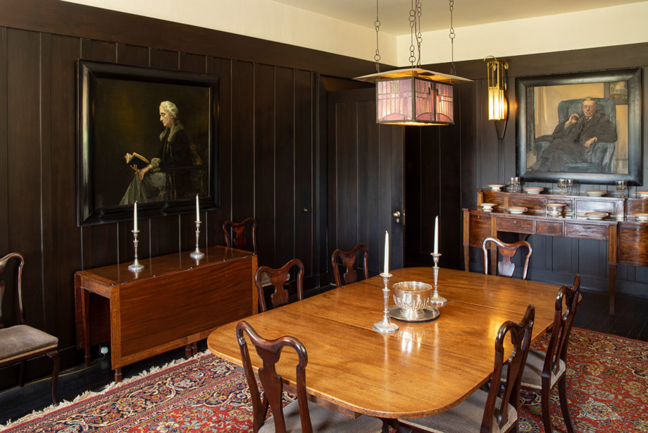 A room with dark wood walls and a table and chairs in the middle of the room