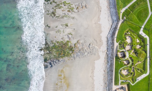 An aerial view of a historic coastal settlement on the very edge of the beach
