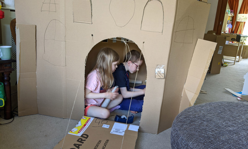 Boy and girl in a castle den made out of cardboard