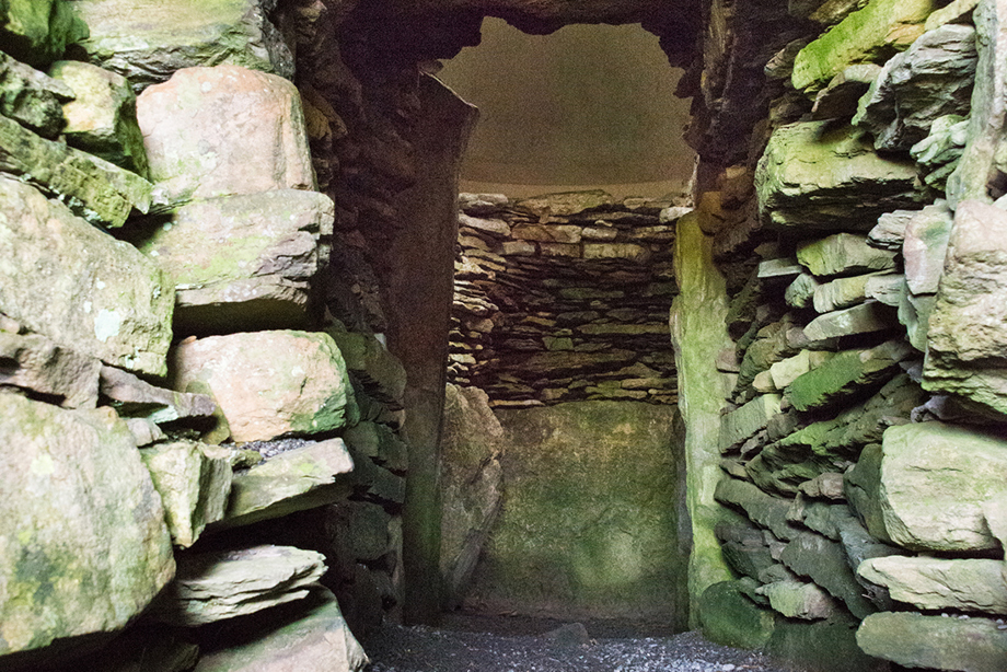 A low and narrow entrance to a monument, with stone walls on either side
