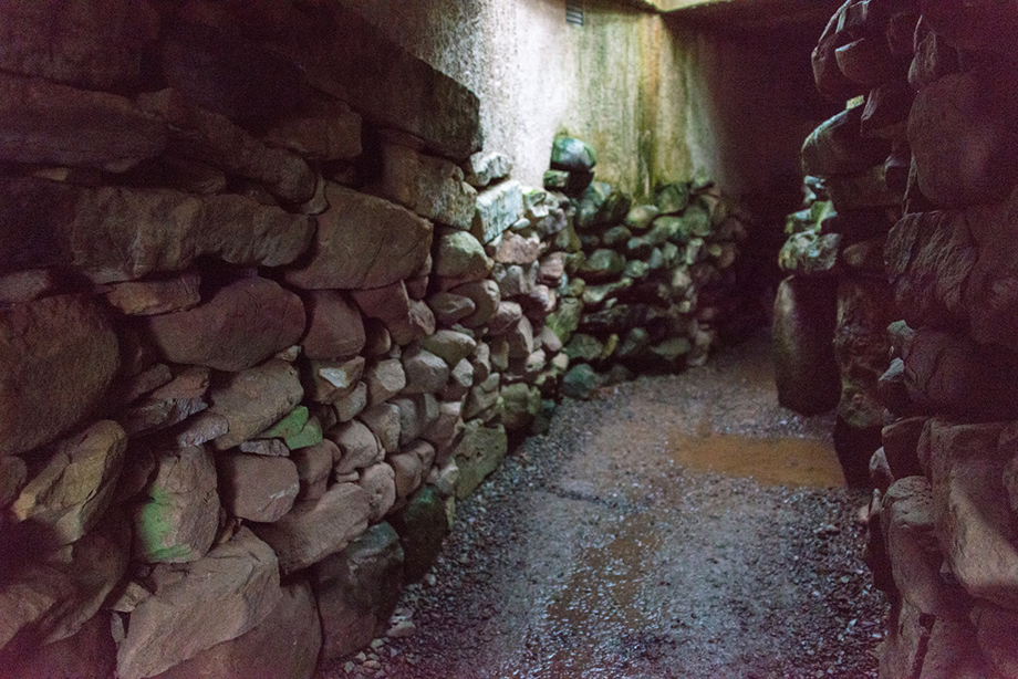 A low and narrow passageway, with stone walls on either side 