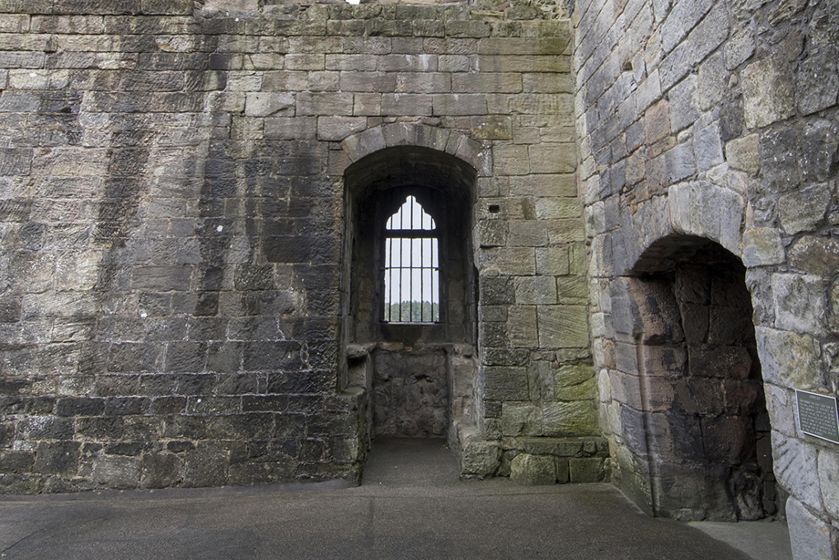 A ruined room with a fireplace and window