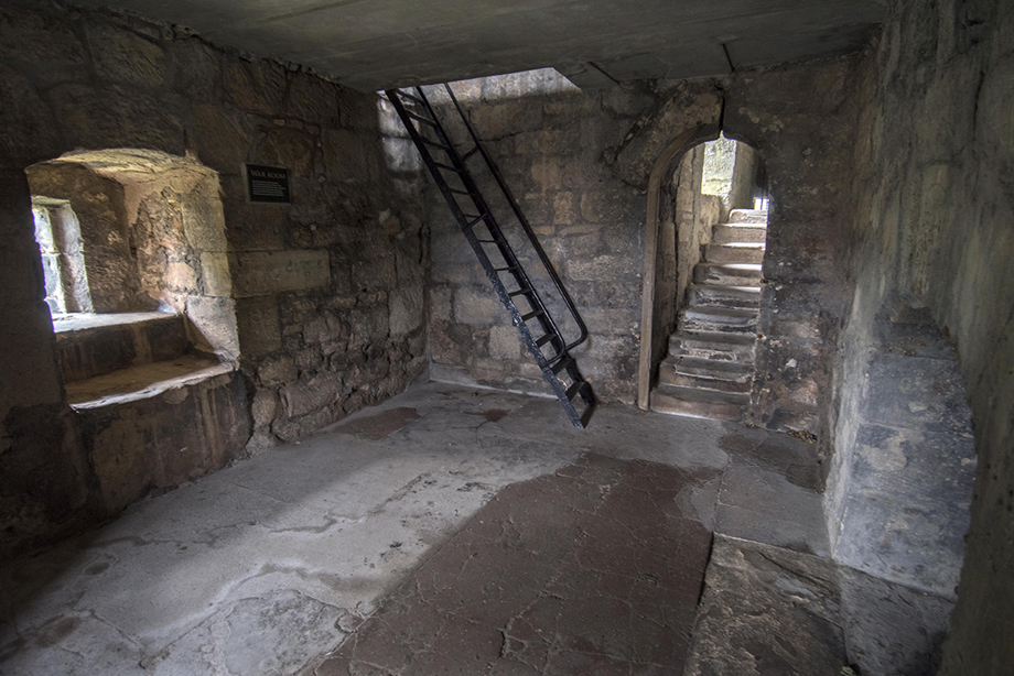 Inside a ruined room with a stone staircase leading in and a metal staircase leading to the floor above