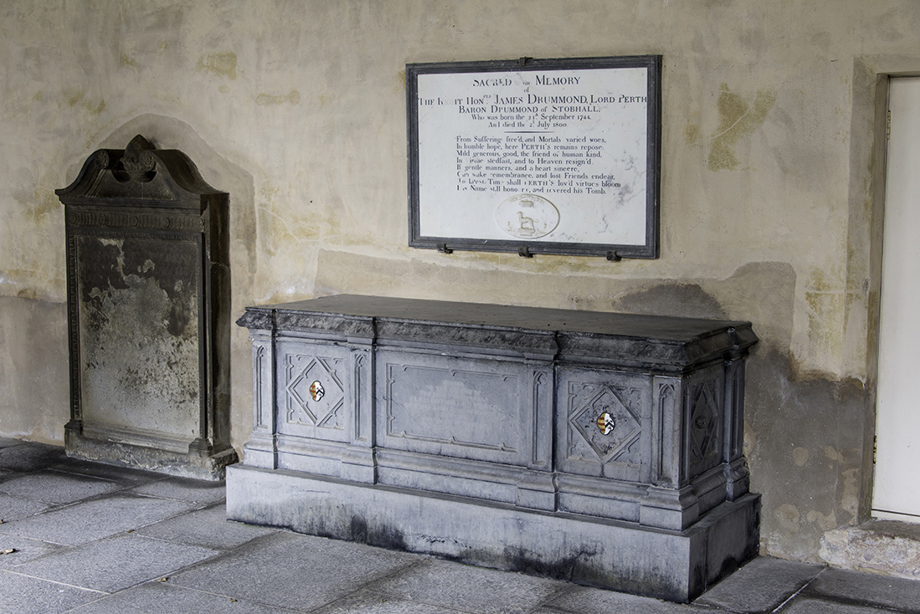 A room with a grave stone and a chest tomb