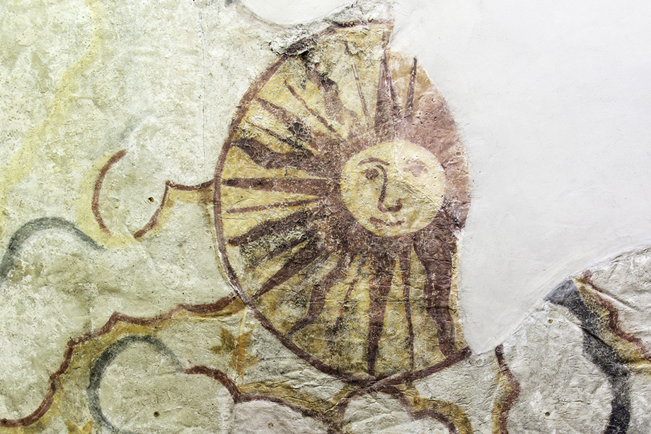 Close up of a historic painting of the sun with a face