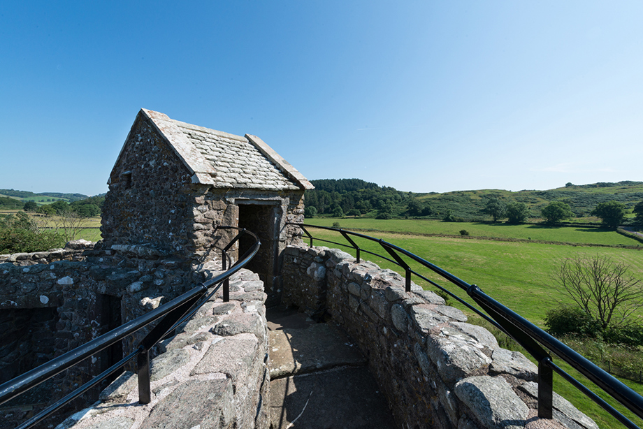 A fenced walkway around the top of a circular tower with no roof.