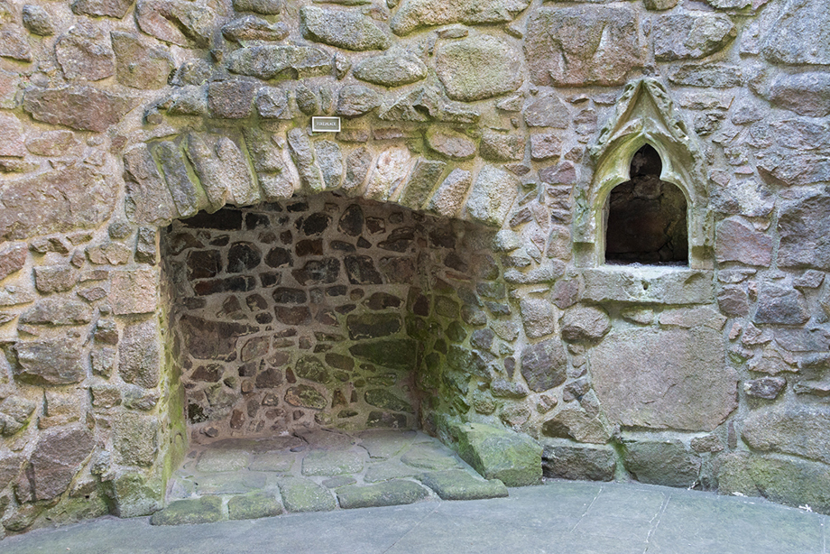 A large stone fireplace, with a decorative shelf to its right.