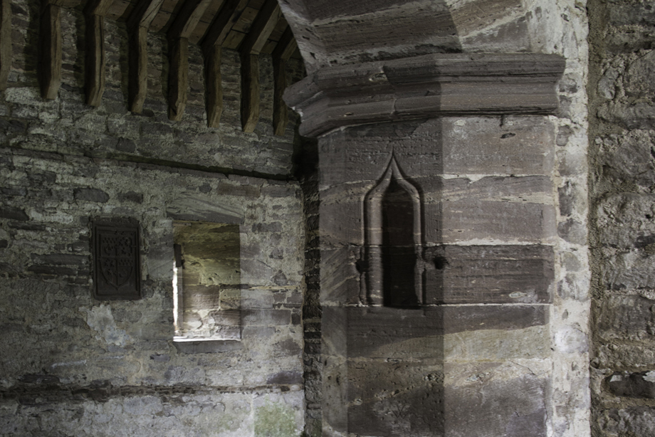 A large stone archway leading to a room with a wooden timber roof.
