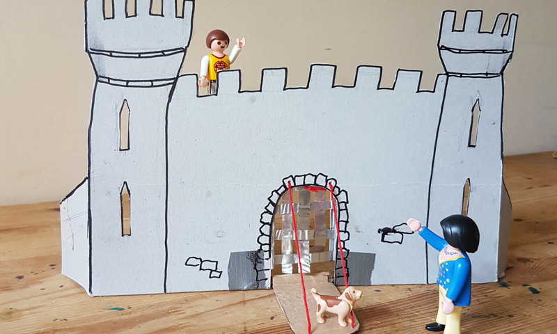 A picture of a castle stronghold made out of cardboard accessorised with lego people