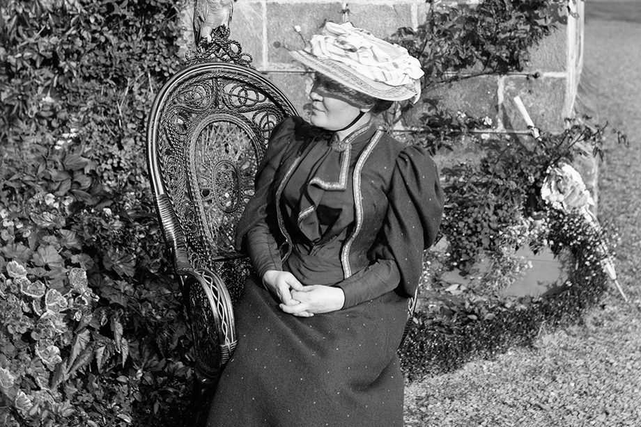 Black and white photograph of a woman sitting outside Culross Abbey House, Fife.