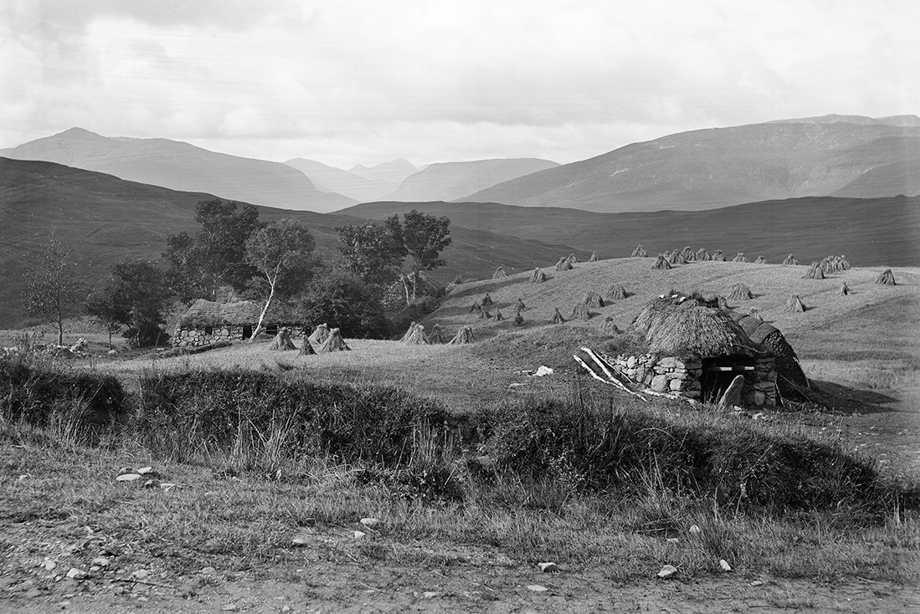 A farmstead with a low, thatched house and byre to the left, and a cart-shed to the right.