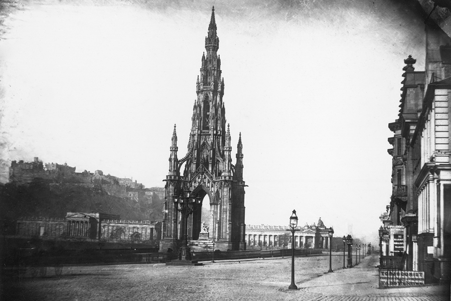 A tall, Gothic monument towering beside a large street 
