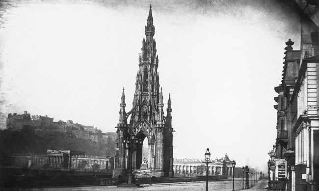 A tall, Gothic monument towering beside a large street 