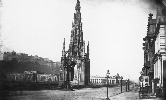 A tall, Gothic monument towering beside a large street 