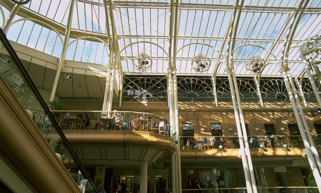 A multi-storey shopping arcade with an iron and glass roof