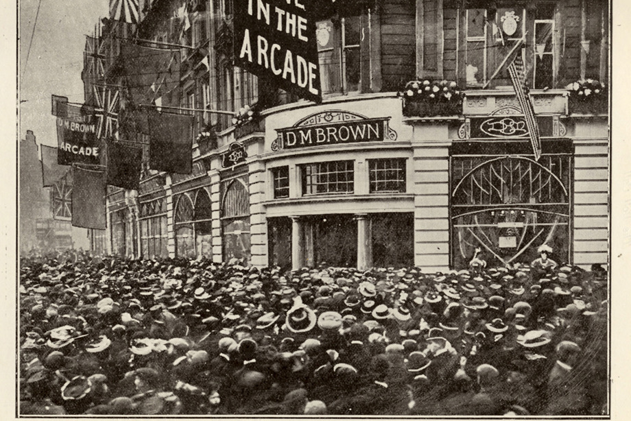 A packed crowd of people on the street outside D.M Browns