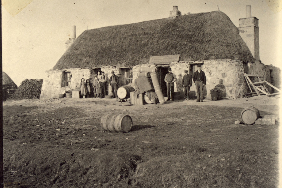 People standing outside a rural, thatched cottage