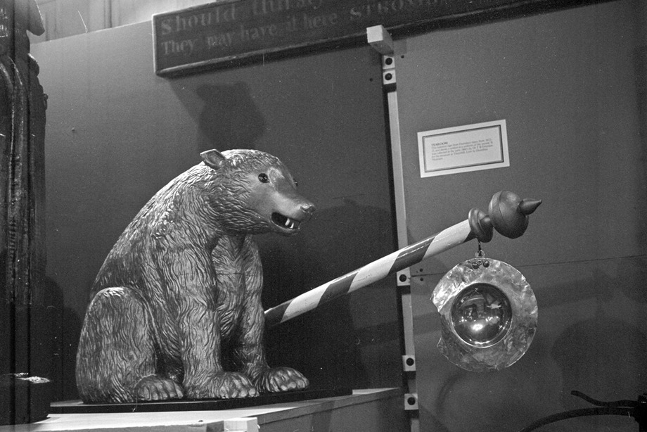 A large bear sculpture with a long barber pole attached