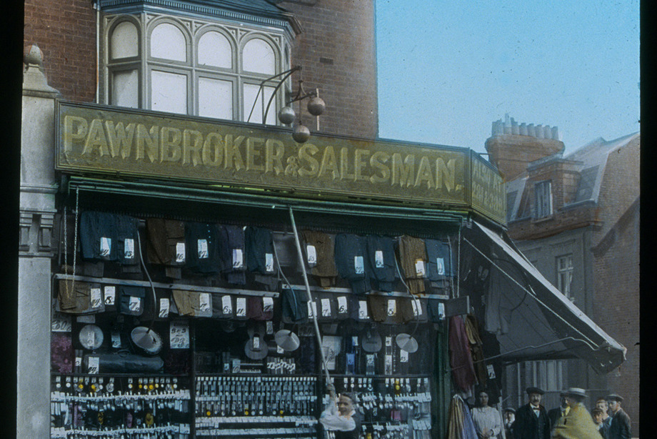 A person cleaning the windows of a large pawnbroker shop