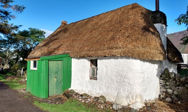 small thatched cottage with a green outhouse