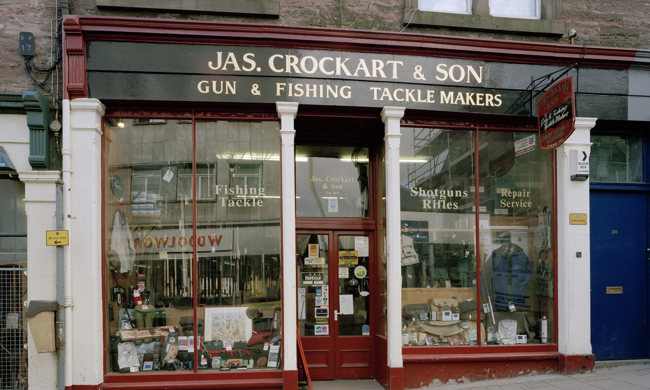 A historic shopfront with full length windows and gold signage