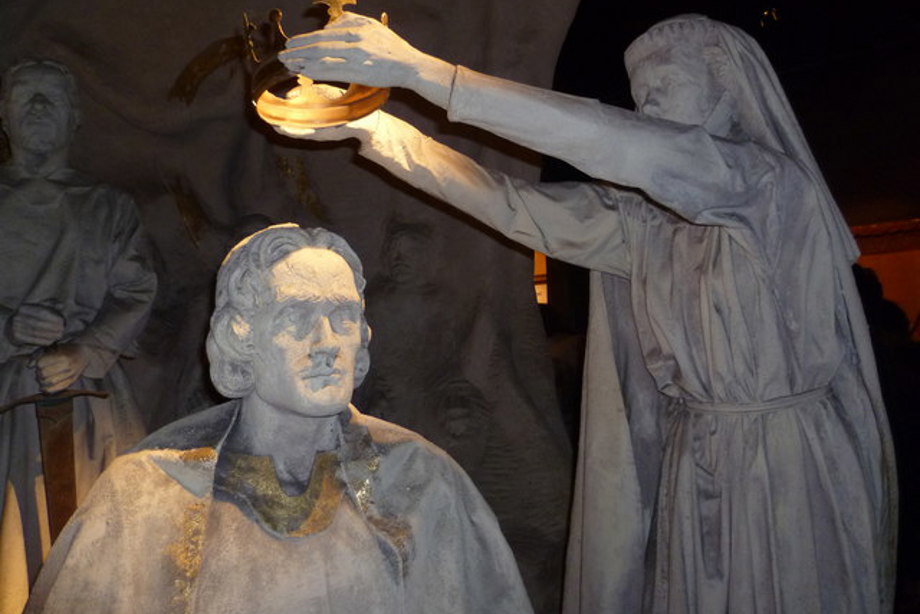 Statues of a woman placing a crown on a man's head.