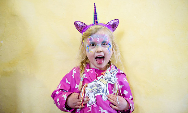 A girl with her face painted and dressed as a unicorn