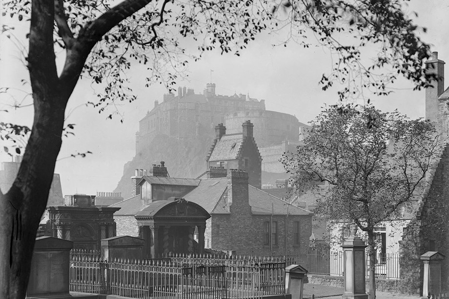 A haunting scene of Edinburgh Castle viewed through a misty graveyard.