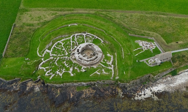 A historic stone broch surrounded by grass