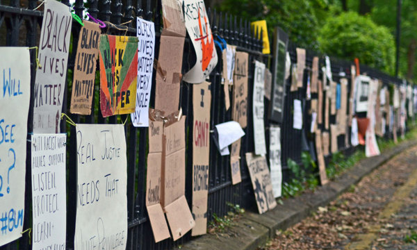 Cardboard placards reading Black Lives Matter fastened to metal railings