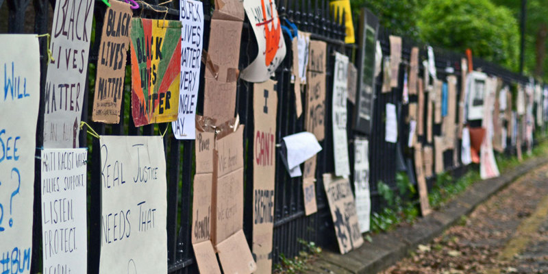 Cardboard placards reading Black Lives Matter fastened to metal railings