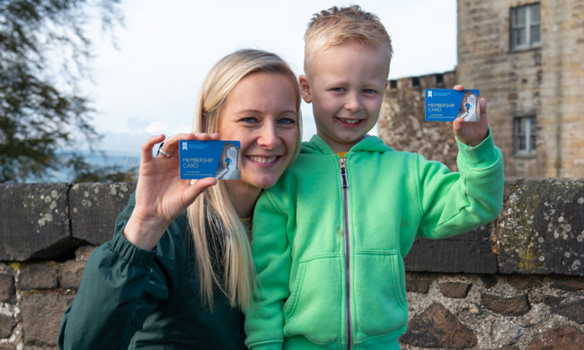 Mother and son holding up their membership cards at Stirling Castle
