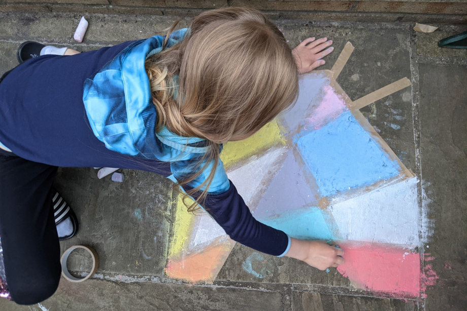 A child making a chalk window on concrete slabs