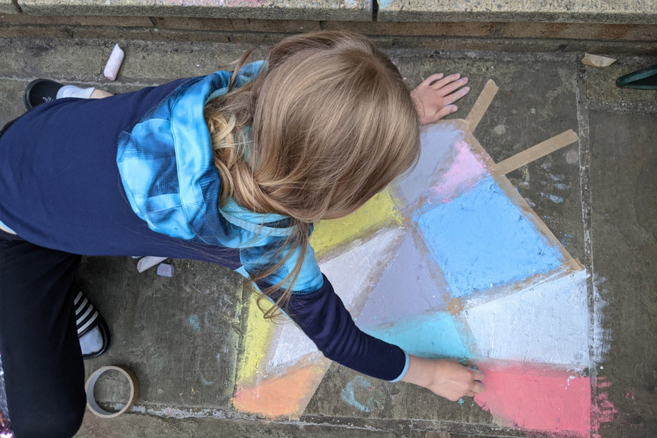 A child making a chalk window on concrete slabs