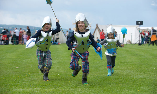Children running towards camera wearing helmets, body armour and shields