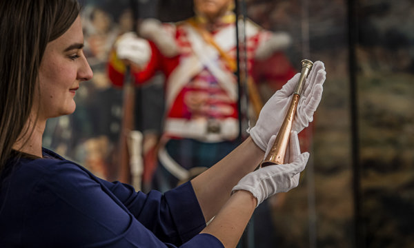 A woman in The Argyll and Sutherland Highlanders Museum and holding an item that is on display