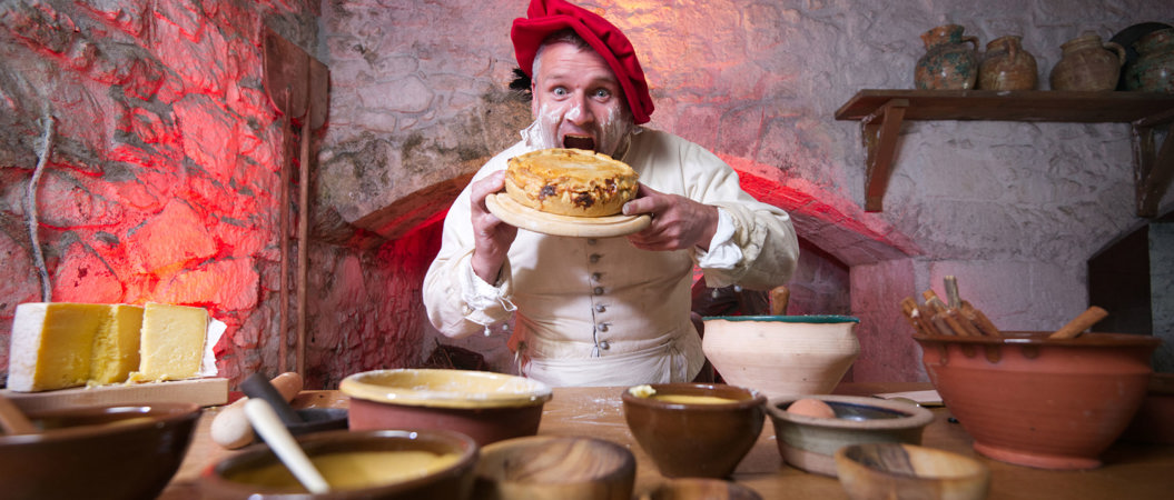 A costumed performer dressed as a cook and holding a large pie in the Great Kitchens at Stirling Castle