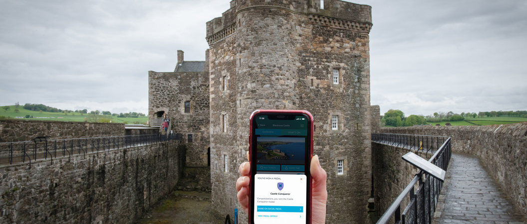 A mobile phone being held in front of Blackness Castle