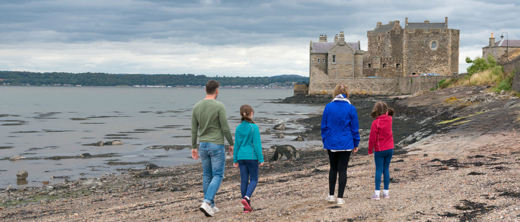 Visitors walking along the water at Blackness Castle