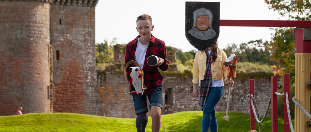 A child with a prosthetic limb pretending to be a knight and jousting at Caerlaverock Castle