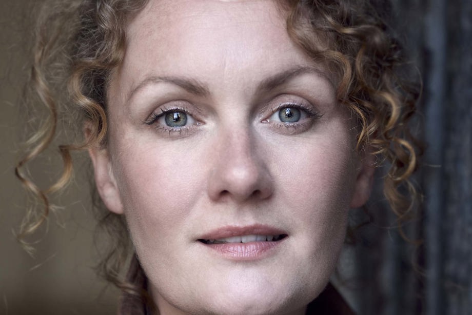 A person with curly hair wearing a top with a collar