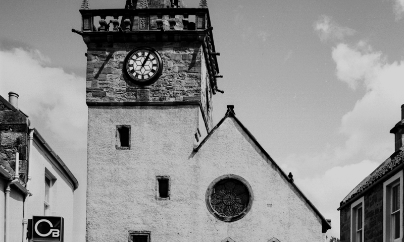 a large, square 16th century tolbooth tower with a lower 19th century prison building attached