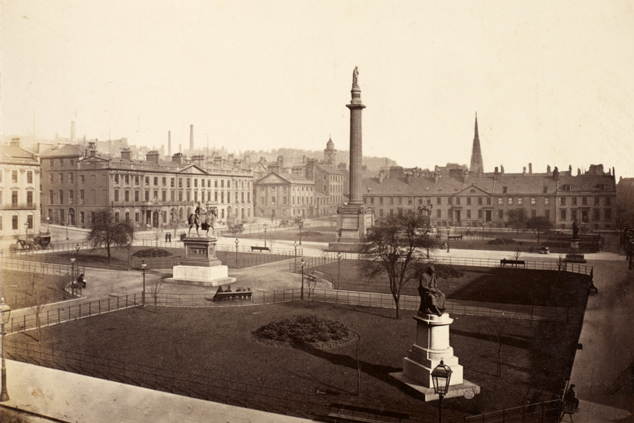 Monuments in a large park dotted with Victorian street lights and people sitting on park benches