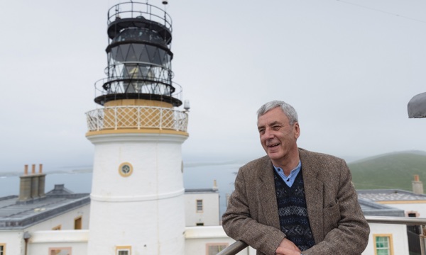 A person standing in front of a historic lighthouse
