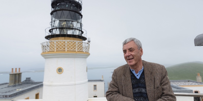 A person standing in front of a historic lighthouse