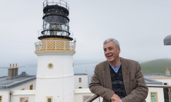 A person standing in front of a historic lighthouse