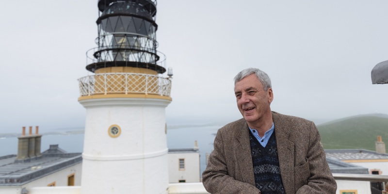A person standing in front of a historic lighthouse