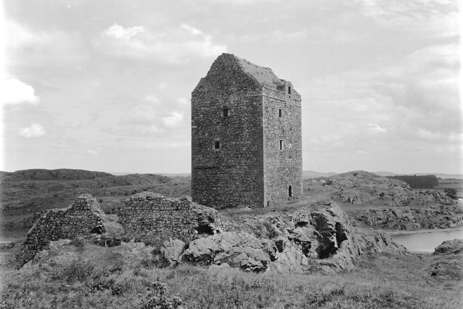 A tower house with small windows and ruined walls nearby.