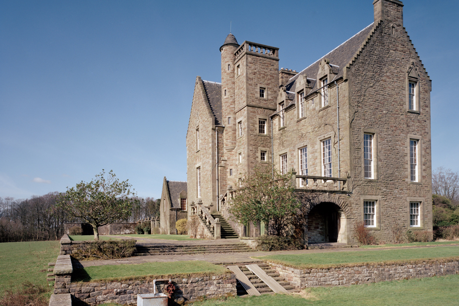 A stone castle with large windows and large grounds