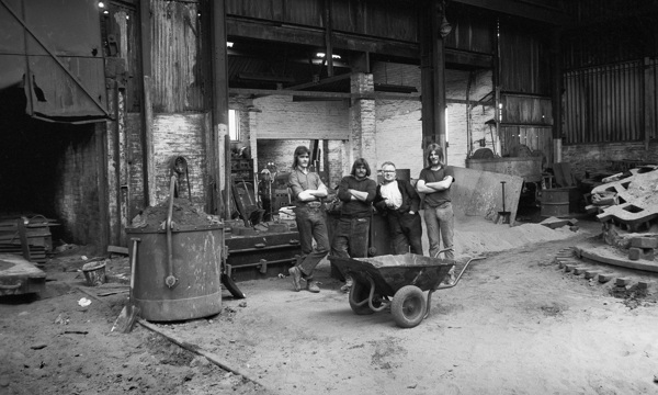 Four people standing in an industrial workshop